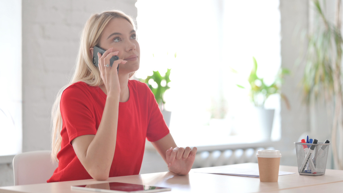 Young Blonde Woman Talking on Phone in Office